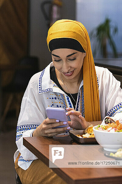 Schöne Frau  die ein Smartphone benutzt  während sie am Tisch im Restaurant sitzt