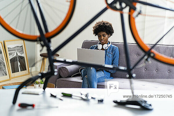 Junge Frau mit Laptop auf dem Sofa  gesehen durch ein Fahrrad zu Hause