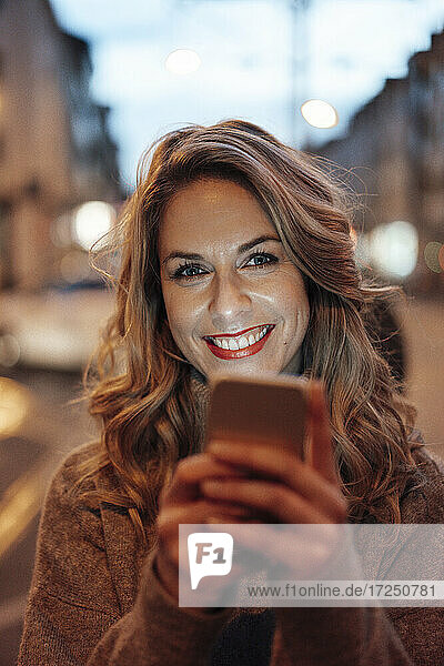 Mittlere erwachsene Frau lächelt und hält ein Smartphone