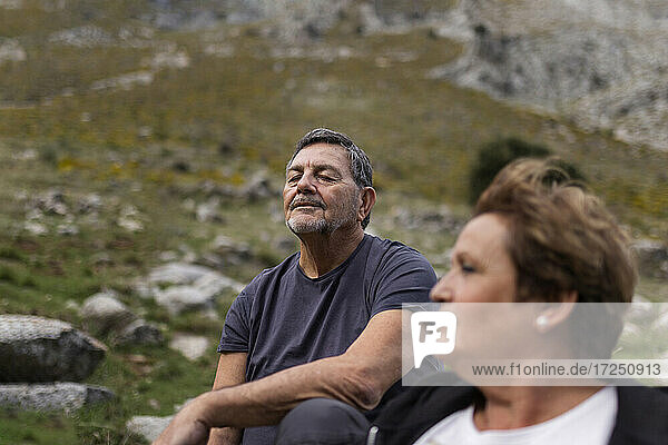 Ältere Frau mit einem Mann im Hintergrund  der eine Pause in den Bergen macht