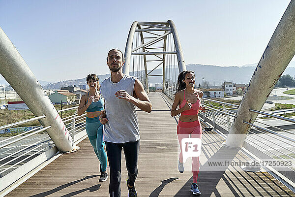 Multi ethnic health conscious friends running on bridge
