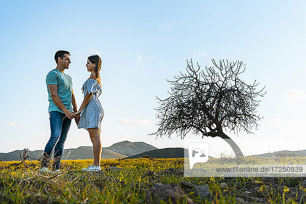 Junges Paar  das sich auf einer Wiese stehend ansieht