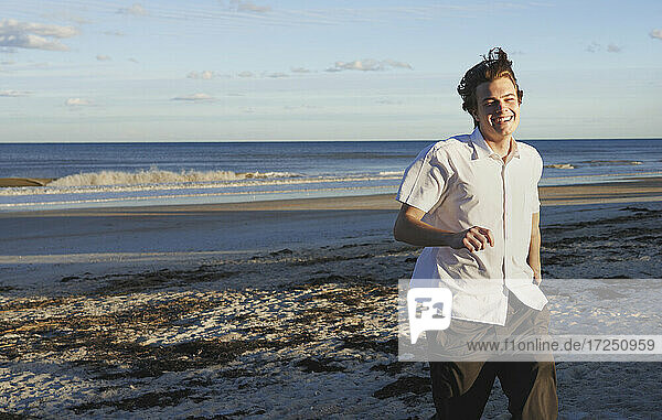 Lächelnder junger Mann läuft am Strand