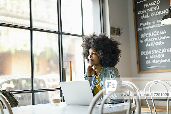 Nachdenkliche Frau mit Laptop in einem Café sitzend