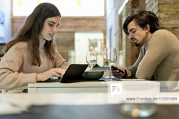 Junges Paar nutzt drahtlose Technologie am Restauranttisch