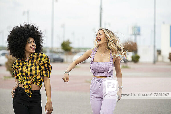 Happy female friends walking on road outdoors