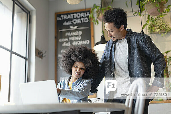 Männlicher und weiblicher Unternehmer arbeiten an einem Laptop in einem Café