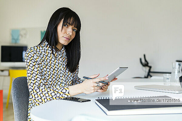 Weibliche Fachkraft hält Grafiktablett am Schreibtisch im Büro