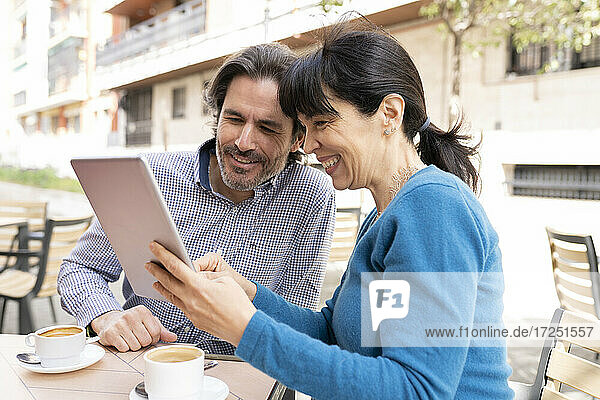 Couple using digital tablet while sitting at terrace