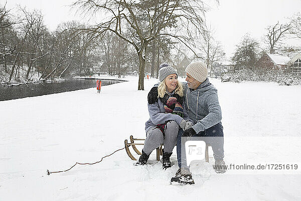 Couple sitting on sled during winter