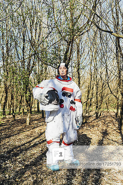 Weibliche Astronautin mit Weltraumhelm in einem Wald stehend