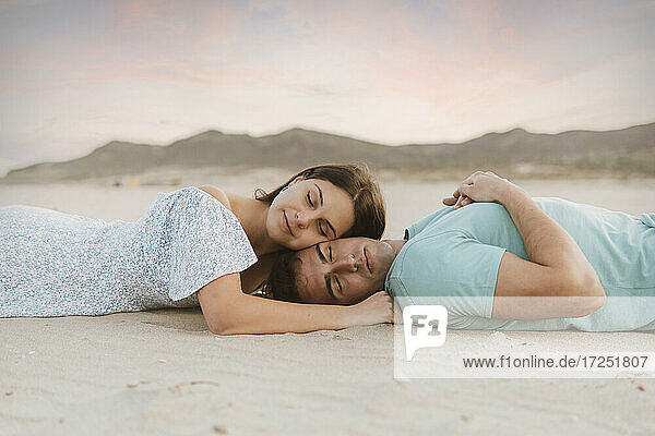 Freundin lehnt sich bei Sonnenuntergang über Sand an ihren Freund