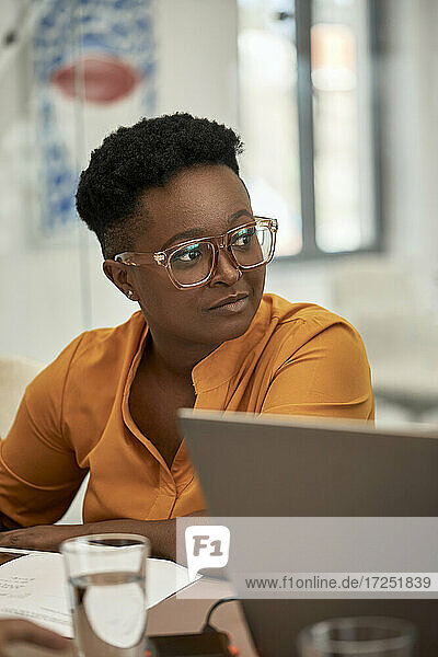 Geschäftsfrau mit Brille schaut im Coworking-Büro weg