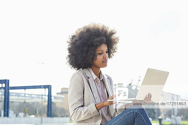 Berufstätige Frau benutzt Laptop im Freien