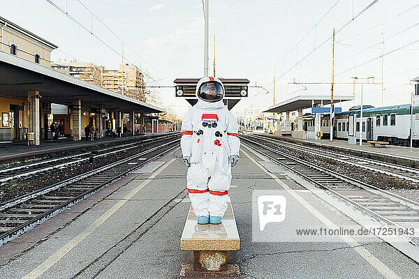 Junge Astronautin steht auf einer Bank am Bahnhof