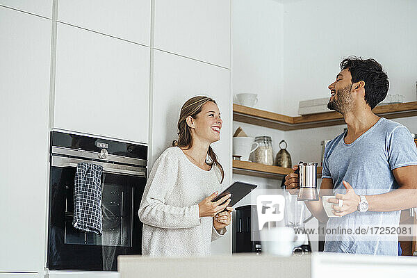 Fröhliches junges Paar  das sich in der häuslichen Küche stehend ansieht