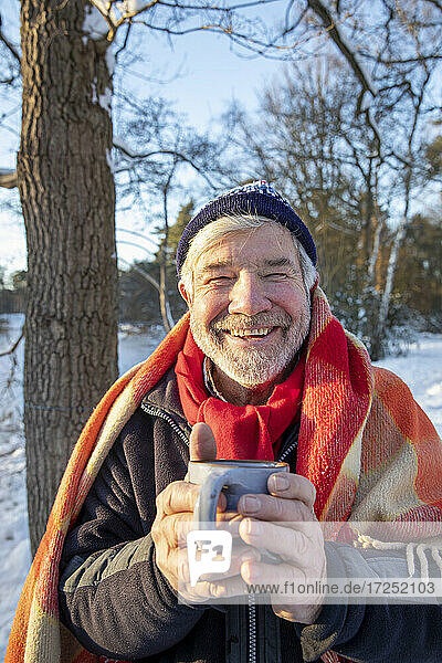 Lächelnder Mann mit Kaffeetasse im Winter