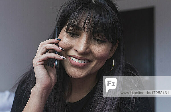 Woman with bangs - hair talking on mobile phone at home