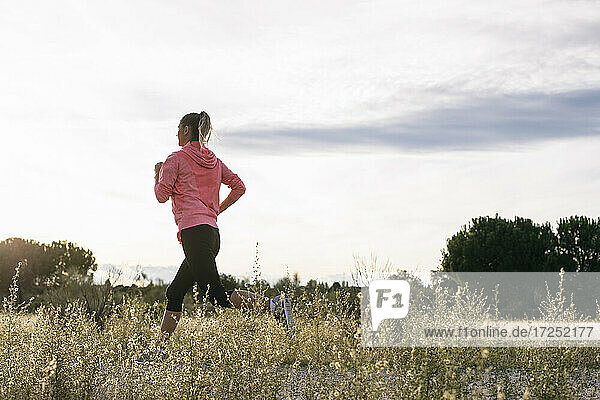 Woman running at agricultural field during sunny day