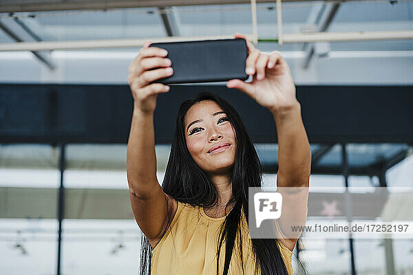 Businesswoman taking selfie from smart phone at office cafeteria