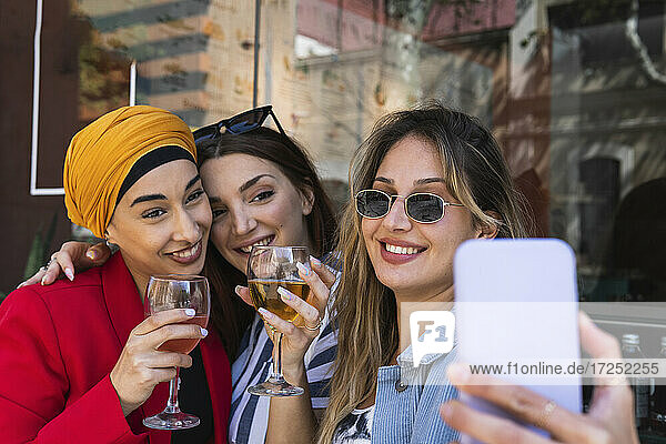 Schöne Frau nimmt Selfie durch Smartphone mit weiblichen Freunden beim Trinken