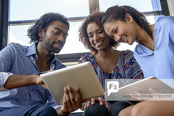 Geschäftsmann beim Brainstorming mit weiblichen Kollegen über ein digitales Tablet im Büro