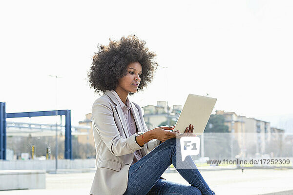 Unternehmerin mit Laptop im Freien sitzend