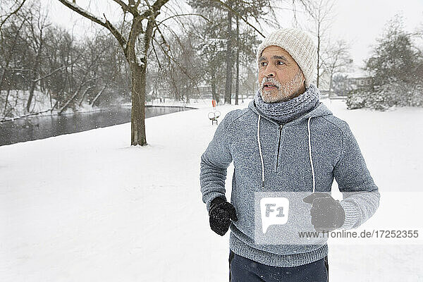 Senior man looking away while running at park during winter