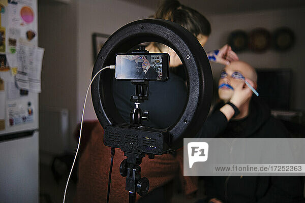 Maskenbildnerin mit Modell beim Vlogging im Studio