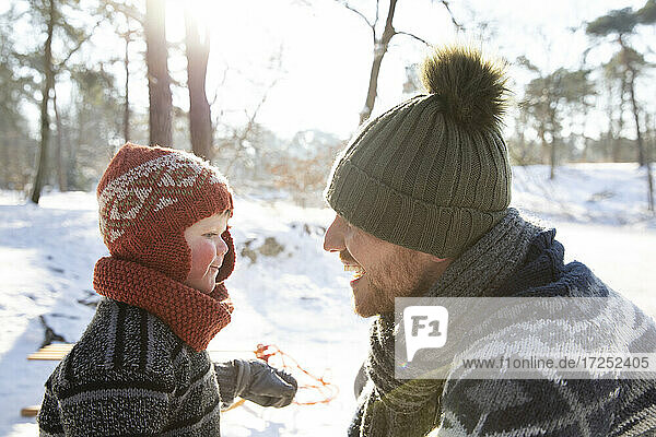 Son looking at smiling father during winter