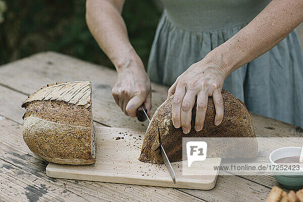 Mature woman slicing bread on table