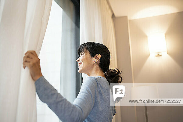 Reife Frau schaut durch das Fenster einer Hotelsuite