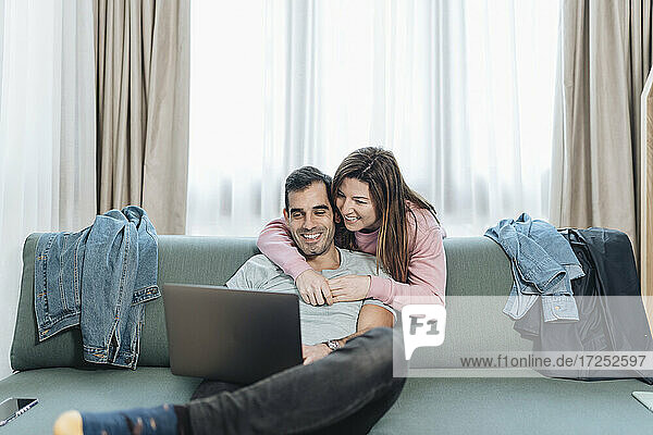 Lächelndes erwachsenes Paar  das im Hotel auf einen Laptop schaut