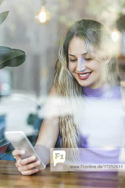 Smiling woman using smart phone in restaurant