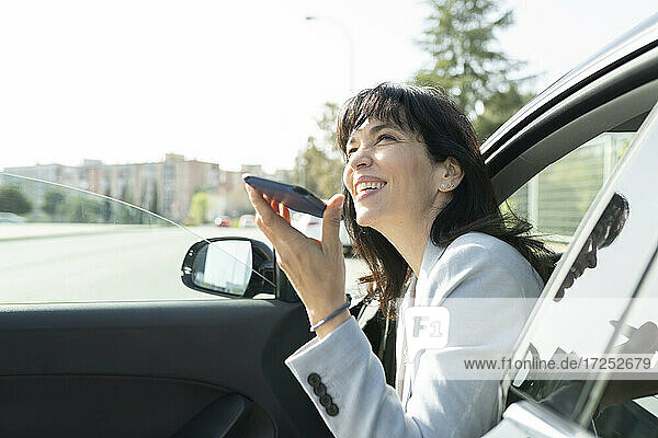 Berufstätige Frau sendet Sprachnachricht  während sie im Auto wegschaut