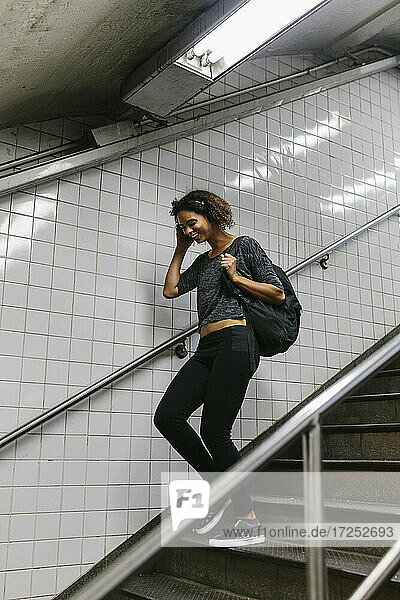 Junge Frau mit Kopf in der Hand  die auf einer Treppe in der U-Bahn nach unten geht