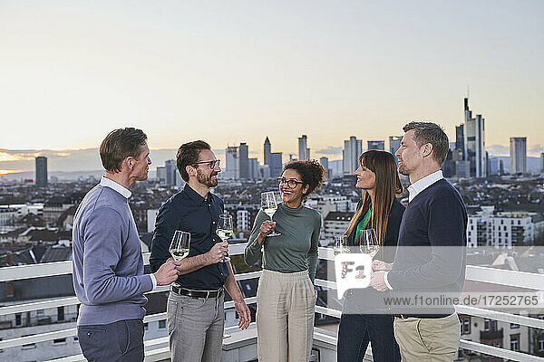 Entrepreneurs with drinks talking in city during sunset