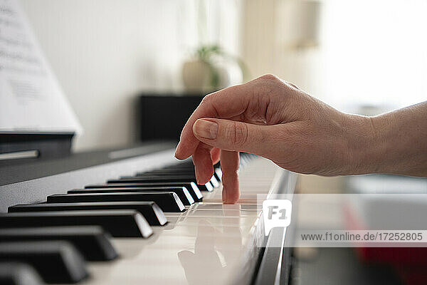 Mittlere erwachsene Frau spielt zu Hause Klavier