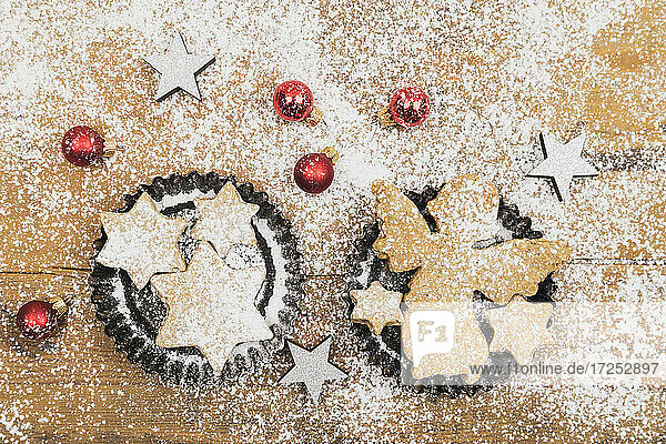 Weihnachtsschmuck und frische  selbstgebackene Kekse auf einer Holzunterlage