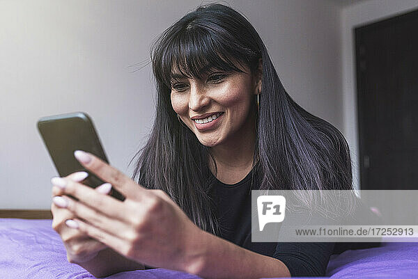 Schöne Frau mit Smartphone auf dem Bett