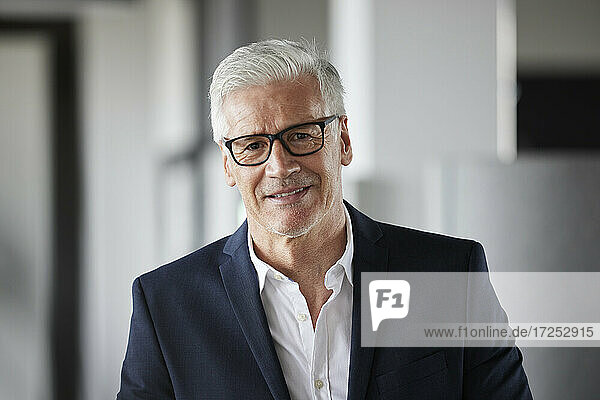 Mature entrepreneur wearing eyeglasses smiling in office