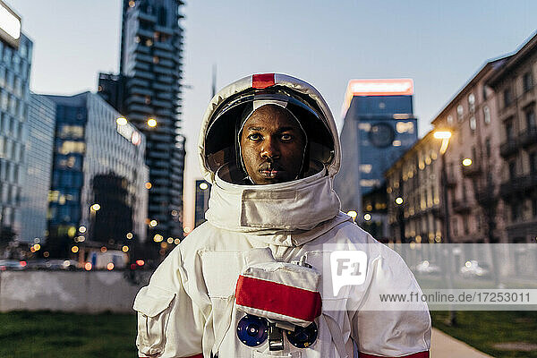 Serious male astronaut standing in front of of building
