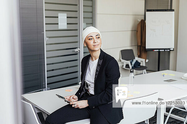 Nachdenkliche Geschäftsfrau sitzt mit digitalem Tablet im Büro