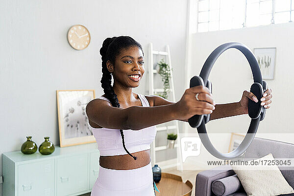Lächelnde Frau  die mit einem Pilates-Ring zu Hause trainiert