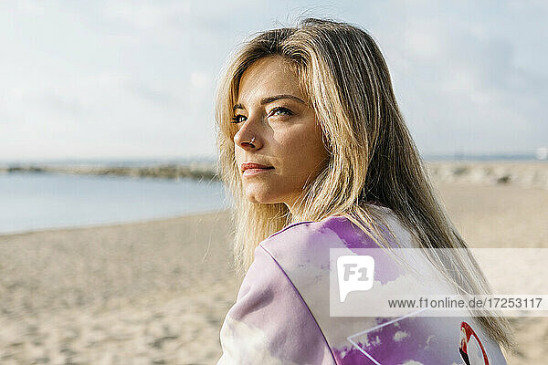 Blond woman looking away at beach