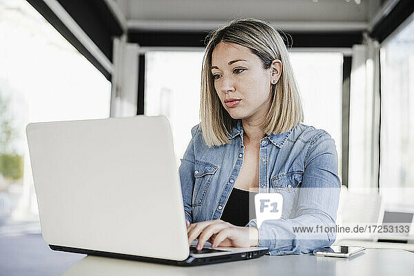 Unternehmerin mit blondem Haar  die in einem Café sitzt und einen Laptop benutzt