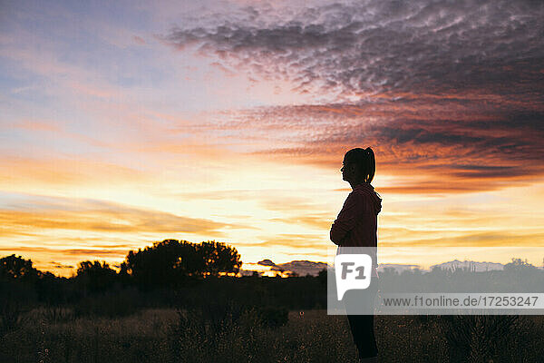 Woman standing in agricultural field during sunset