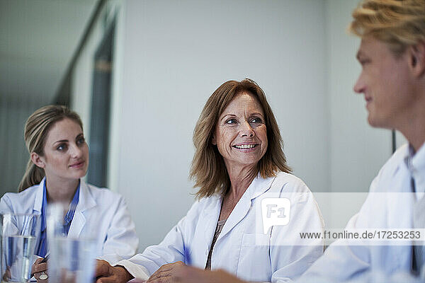 Weibliche Ärzte lächeln ihren männlichen Kollegen im Krankenhaus an