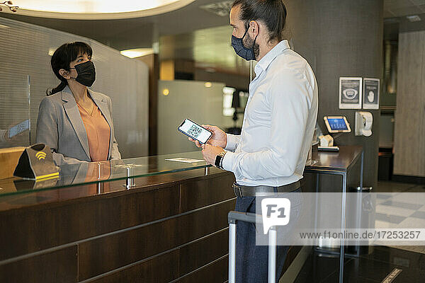 Mature man wearing protective face mask standing at receptionist desk