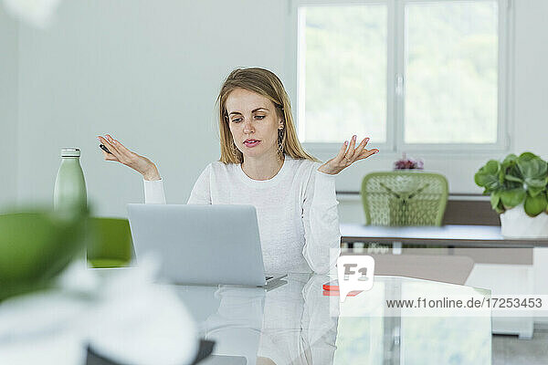 Geschäftsfrau gestikuliert während eines Videogesprächs am Laptop im Büro